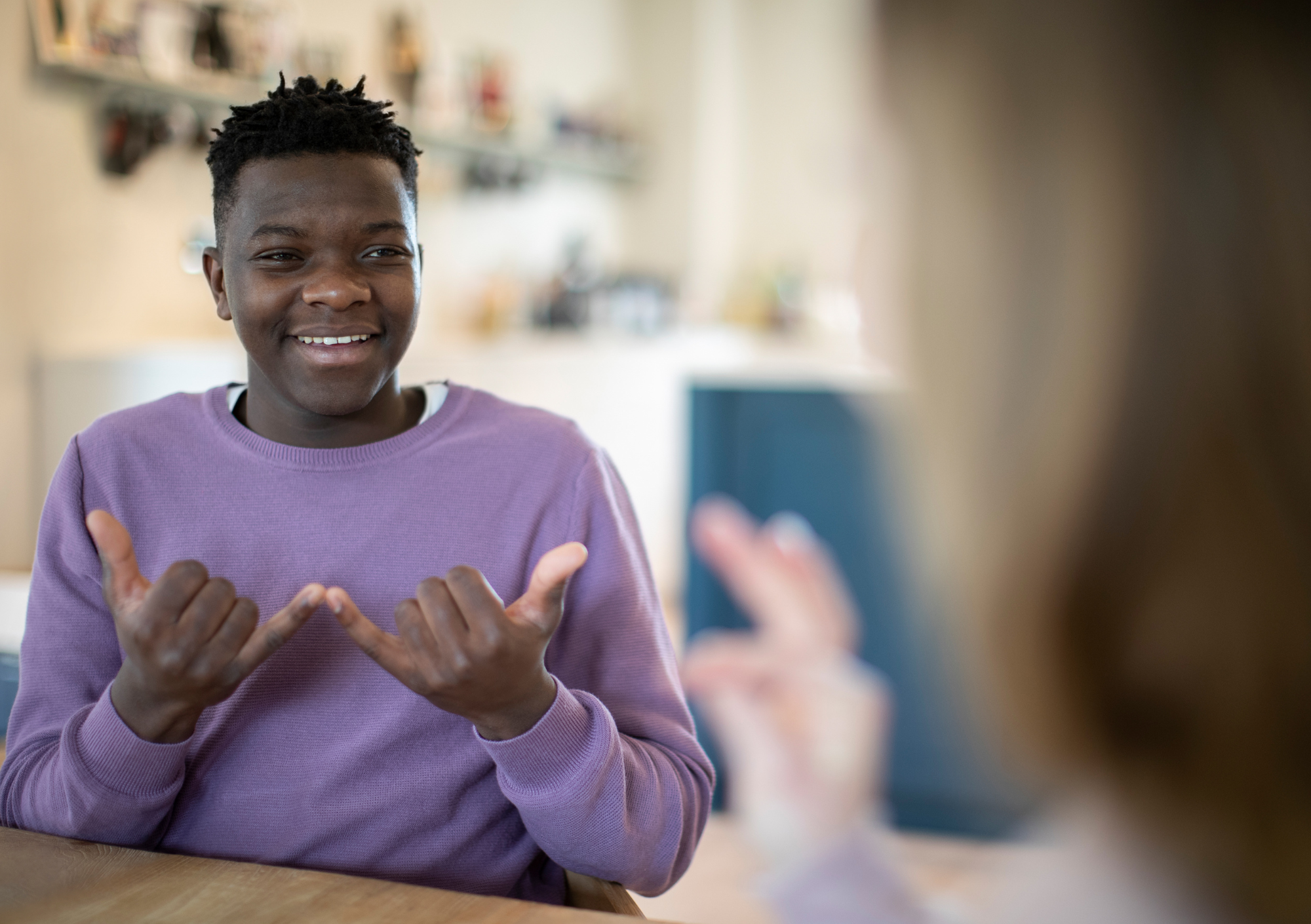 A young person using sign language to communicate with another person.