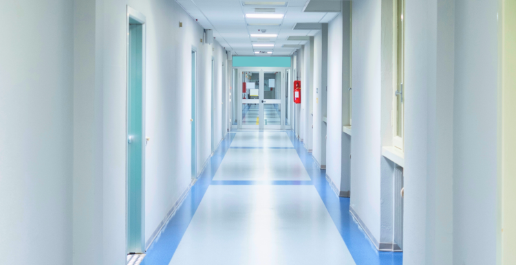 A blue and white hospital corridor with rooms off to each side.