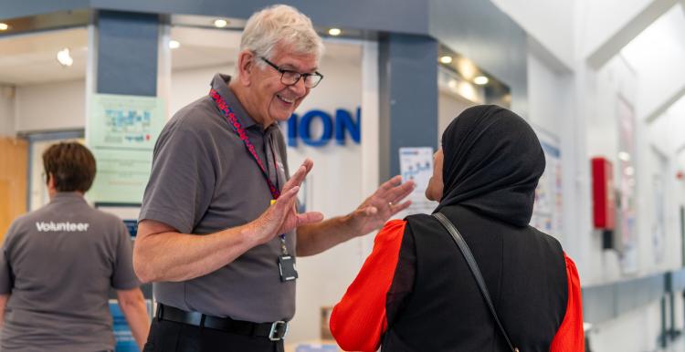 A volunteer talking to a service user or visitor in a hospital corridor.