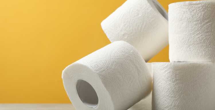 Four rolls of toilet paper stacked against a yellow background.