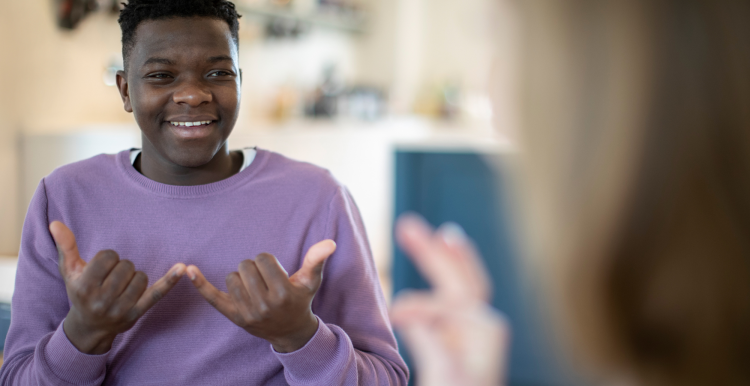 A young person using sign language to communicate with another person.