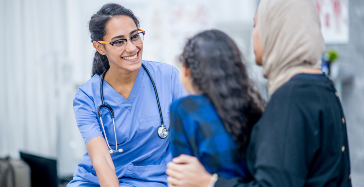 A doctor speaking to a mother and daughter in a doctor's office.
