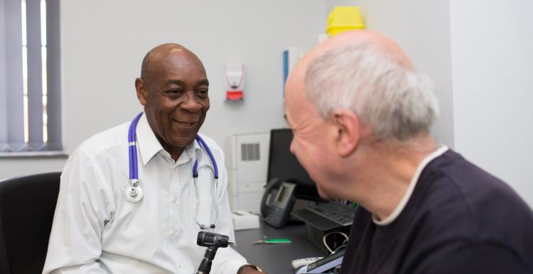 A man sitting in a doctor's office, talking to the doctor