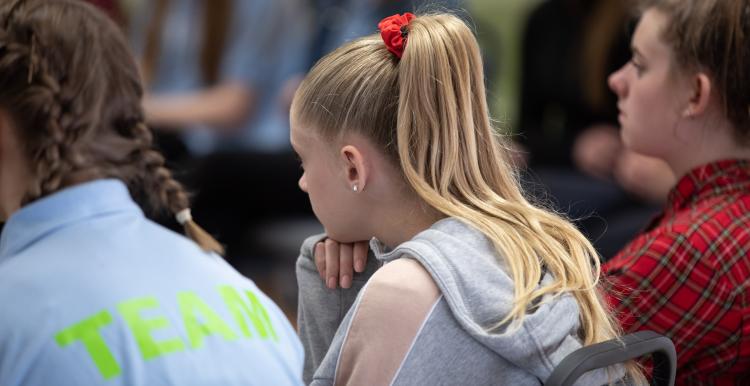 The backs of three young people sitting down