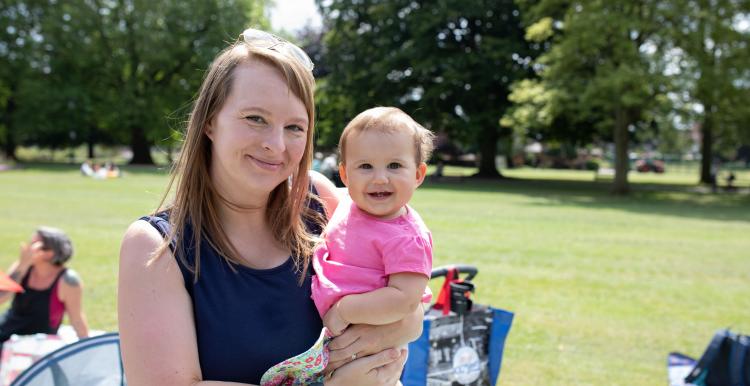 A woman in a park holding a young child