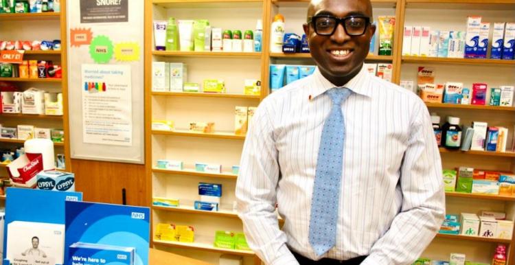 Ade Williams, a man, standing behind a counter in a pharmacy