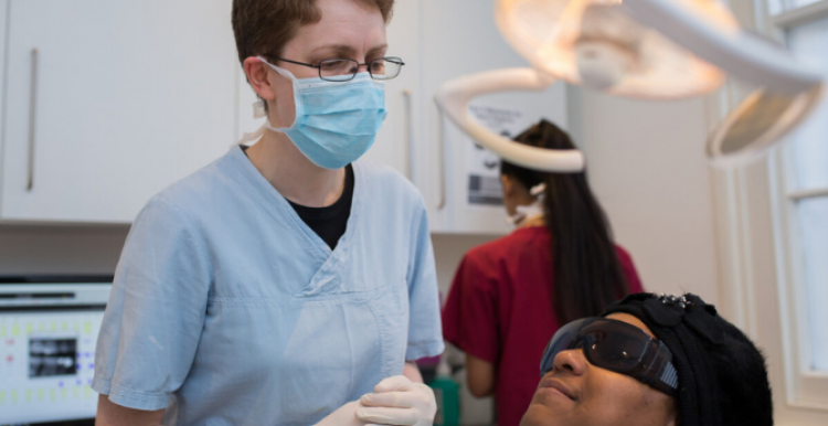 A dentist examines a woman lying on a dentist's chair