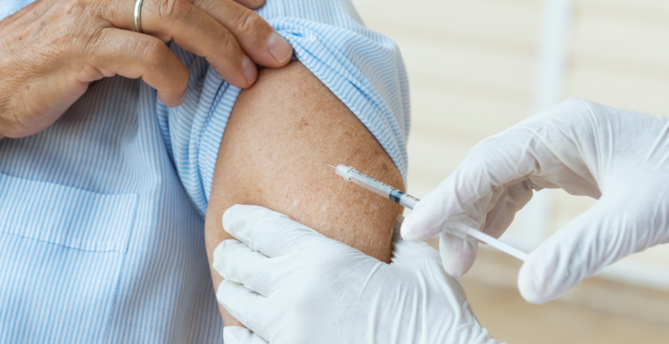 A person getting a vaccination from a person wearing white surgical gloves.