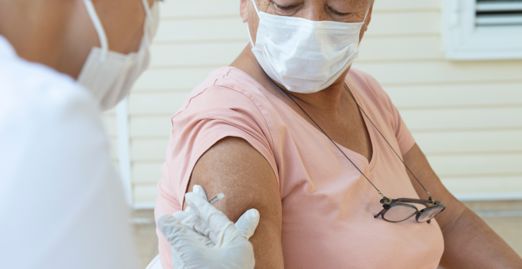 An older woman wearing a face mask receiving a vaccine