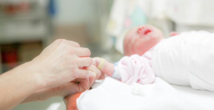 Photo of someone holding the hand of a newborn baby