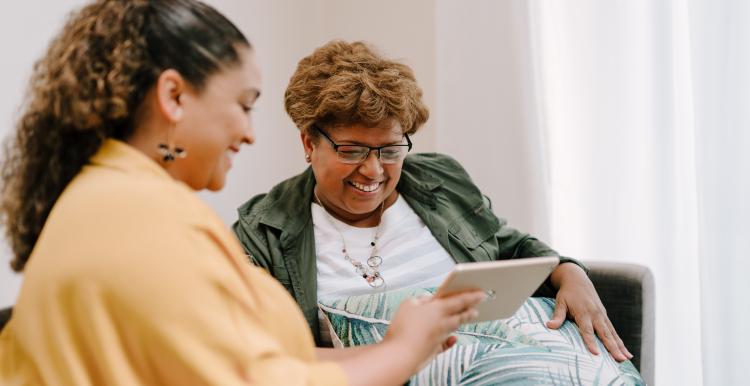 Two people sitting on a sofa looking at a tablet