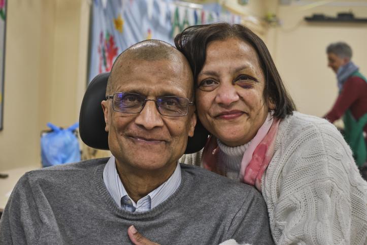 An older couple hugging and smiling. The man is in a wheelchair or powerchair.