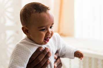 A young Black baby being held up by an adult.