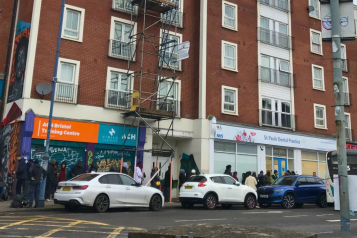 A queue of people in front of St Pauls Dental Practice, lining up on a street in St Pauls, Bristol.