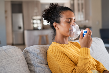 A woman using a nebuliser at home.