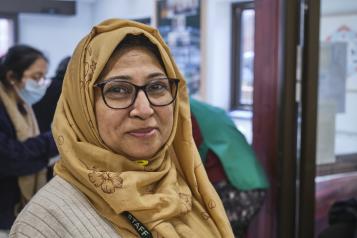 A woman wearing a headscarf smiling.