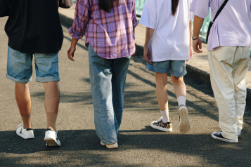 Photo from behind of four young people walking along a road.