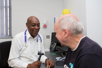 A man sitting in a doctor's office, talking to the doctor