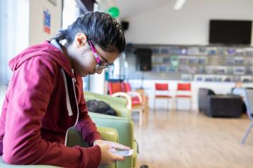 A young woman sitting in a communal room looking at her phone