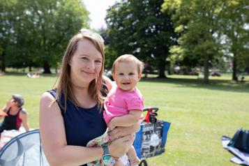 A woman in a park holding a young child