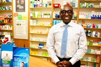 Ade Williams, a man, standing behind a counter in a pharmacy