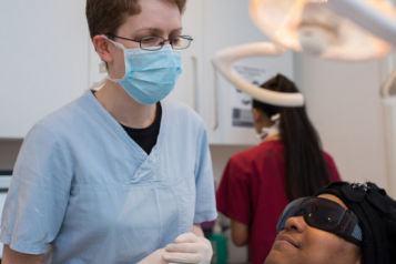 A dentist examines a woman lying on a dentist's chair