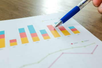 Bar charts with someone using a pen to point to the document