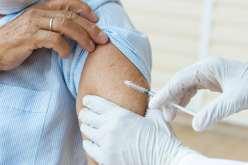 A person getting a vaccination from a person wearing white surgical gloves.