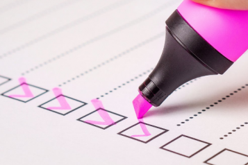 A pink highlighter being used to tick boxes on a list