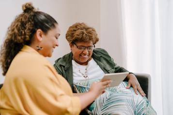 Two people sitting on a sofa looking at a tablet