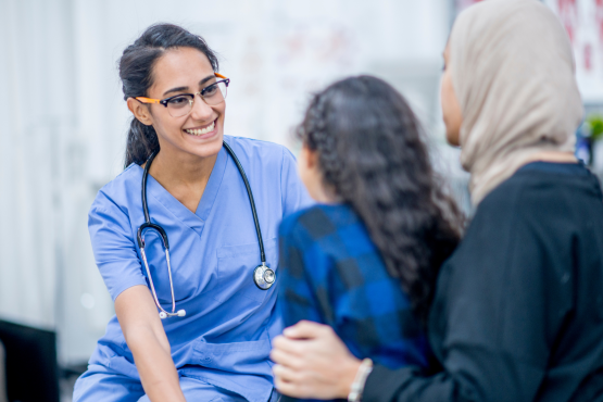 A doctor speaking to a mother and daughter in a doctor's office.