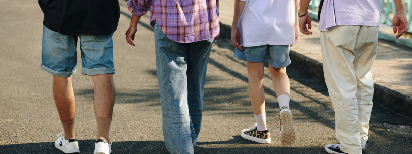 Photo from behind of four young people walking along a road.