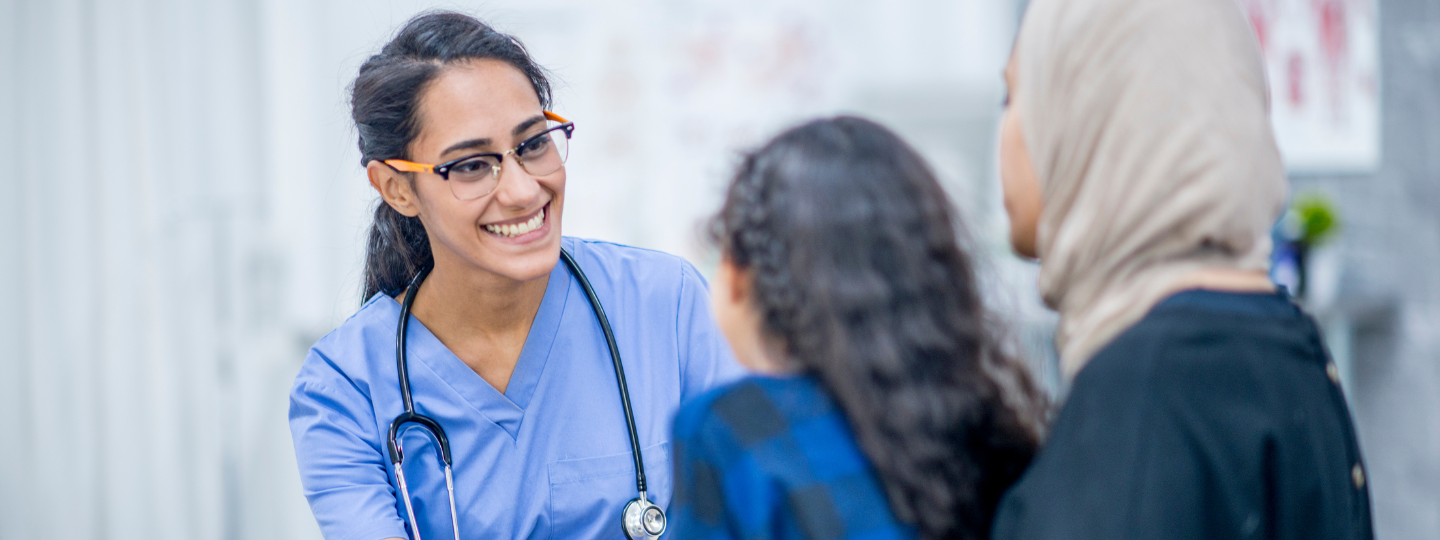 A doctor speaking to a mother and daughter in a doctor's office.