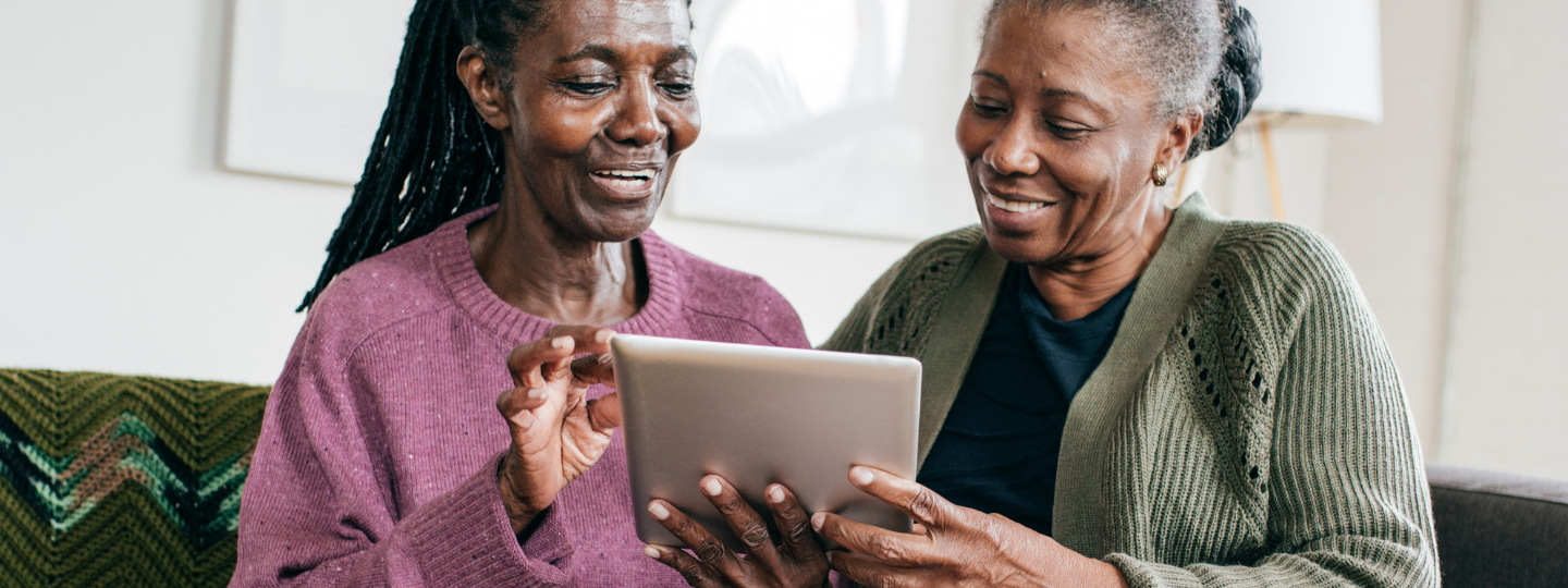 Two woman looking at a tablet and smiling