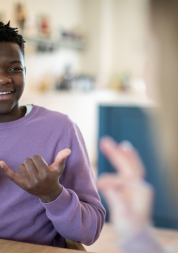 A young person using sign language to communicate with another person.