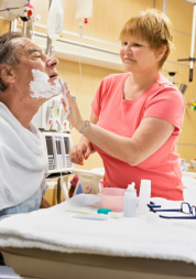 A woman helping a male patient in a hospital bed shave his facial hair A woman helping a male patient in a hospital bed shave his facial hair