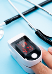 A pulse oximeter on someone's finger with a stethoscope in the background