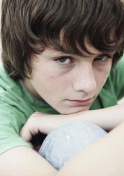 A young boy sitting down hugging his knees